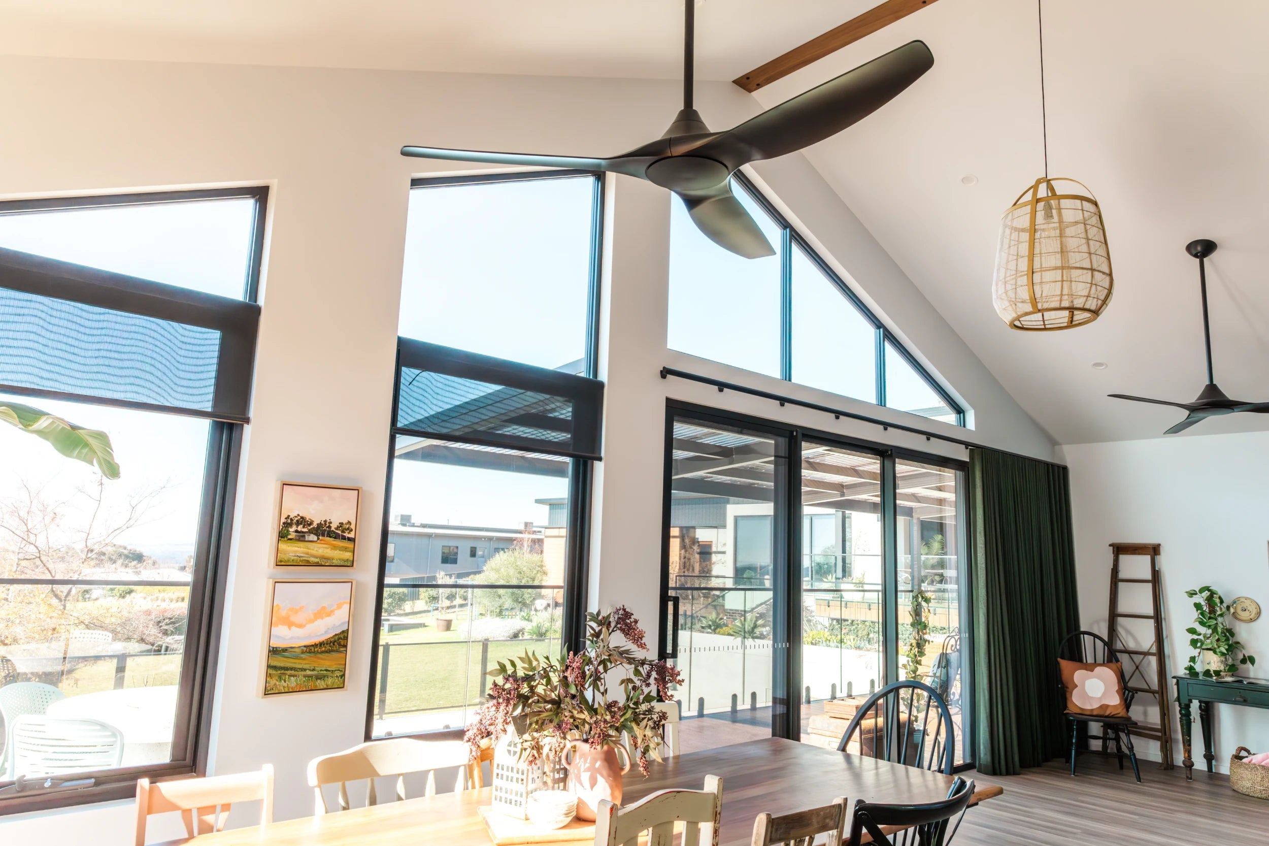 Modern living room with large windows, ceiling fans, and decorative elements.