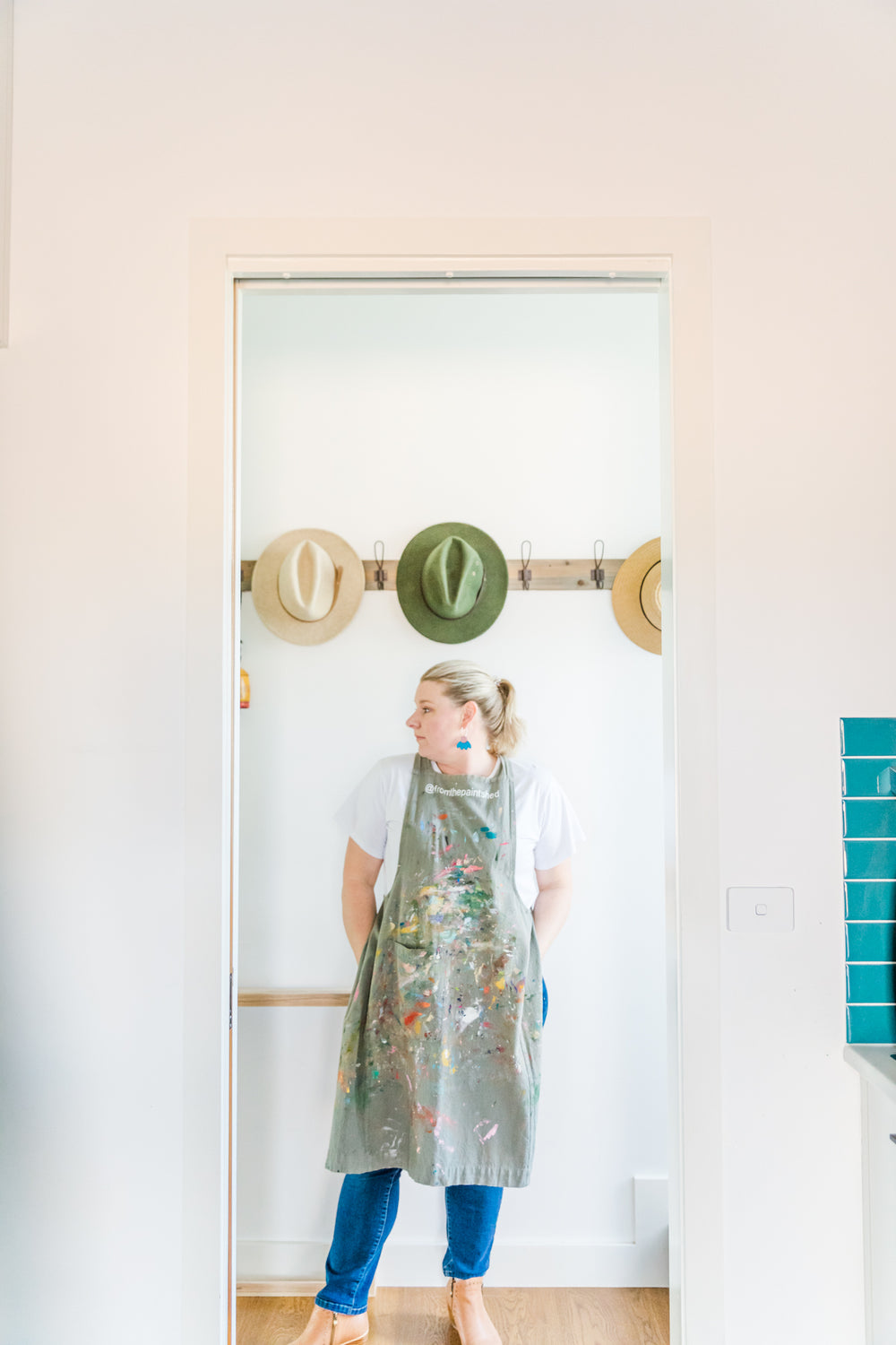 Person wearing a colorful apron standing in a room with a mirror and decorative items on the wall.
